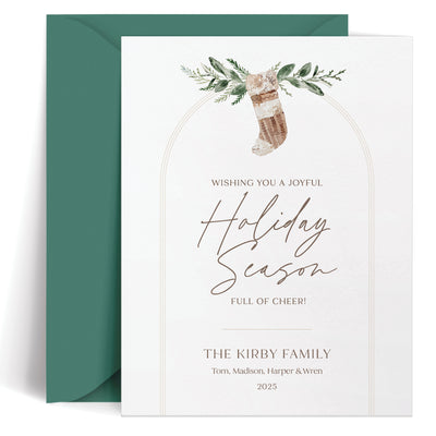 Custom holiday card in a boho design with neutral Christmas stocking and greenery with an arch detail