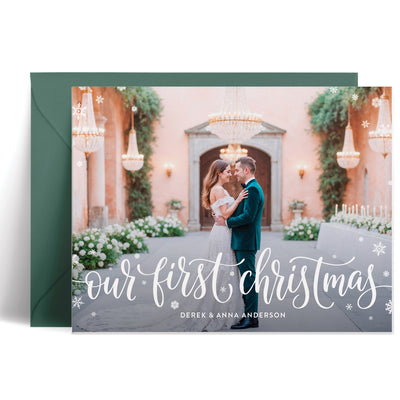 Personalized holiday cards for newlyweds featuring a photo framed in snowflakes with "Our First Christmas" in calligraphy
