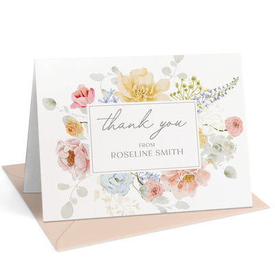 A frame of soft, watercolor florals borders this elegant thank you card personalized with your name