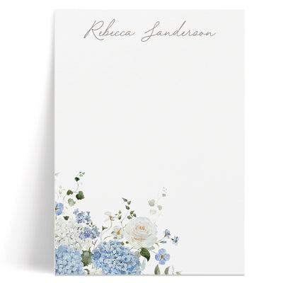 This elegant custom notepad features a classic bouquet of blue hydrangeas and white roses along with your name in script
