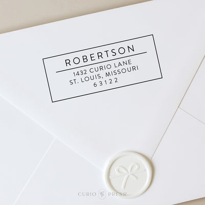 Modern square address stamp design with name and address inside a bold outlined box, divided by a horizontal line