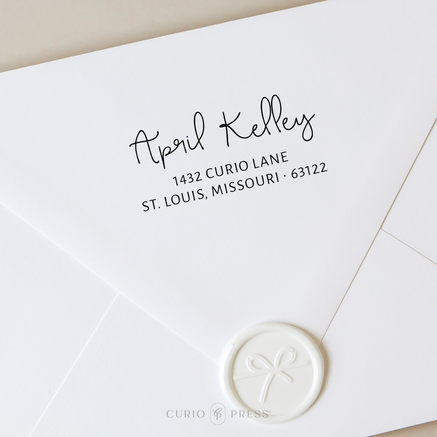Custom address stamp with swash-style script name and clean address text, stamped in black ink on envelope