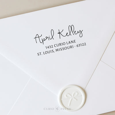 Custom address stamp with swash-style script name and clean address text, stamped in black ink on envelope