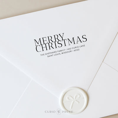Custom holiday stamp with Merry Christmas in a bold font stamped onto a white envelope with wax seal