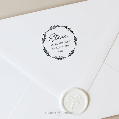 Custom holiday stamp with leaf and berry wreath and a wax seal on a white envelope