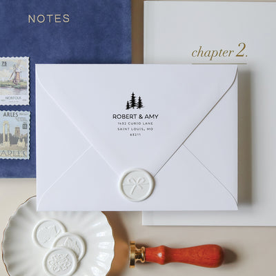 White envelope with personalized address and wax seal, surrounded by stationery items.